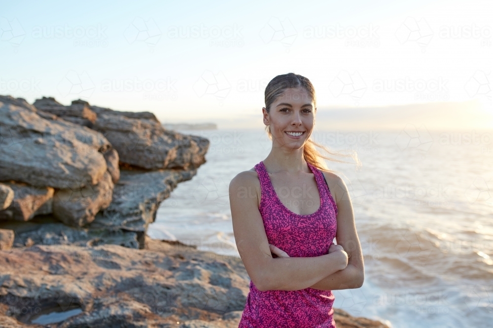 Fitness woman with standing on coastal headland at sunrise - Australian Stock Image