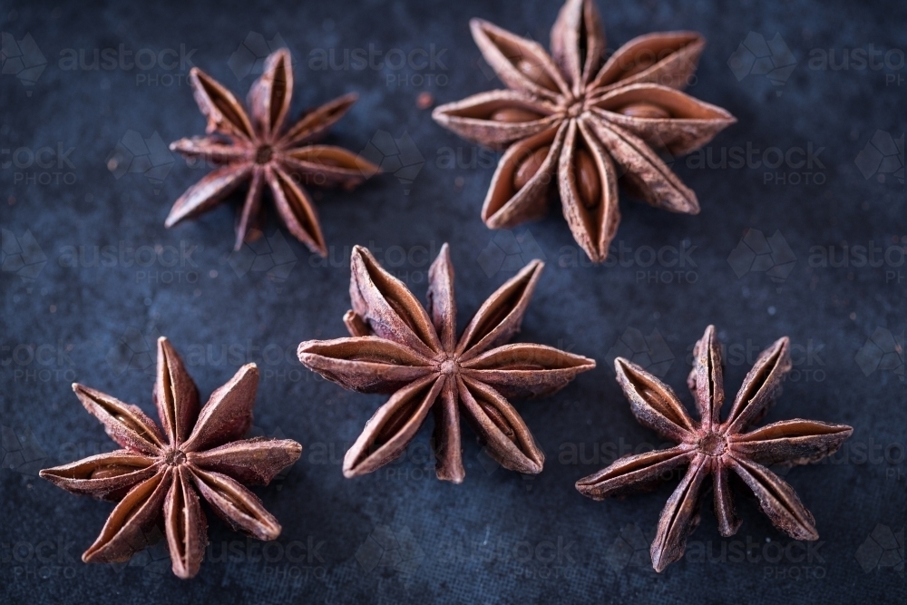 Five aniseed stars on blue tile background - Australian Stock Image