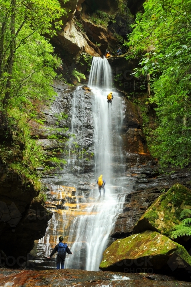 Five people abseiling down and through the waterfall at Empress Falls in the Blue Mountains of NSW - Australian Stock Image