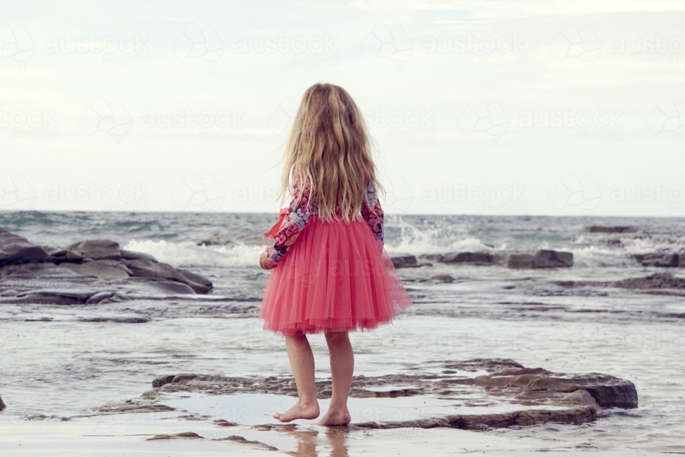 five year old walking along beach looking away - Australian Stock Image