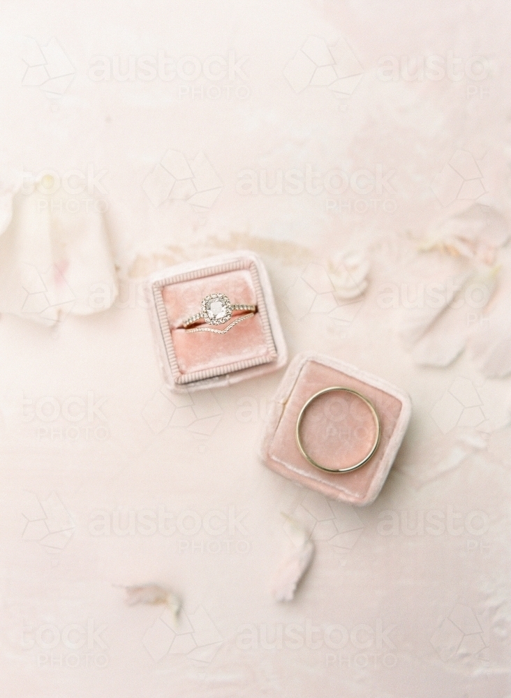 Flat lay of a diamond ring and gold band in pink boxes - Australian Stock Image