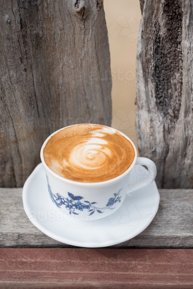 Flat white coffee in a vintage teacup in a rustic setting - Australian Stock Image