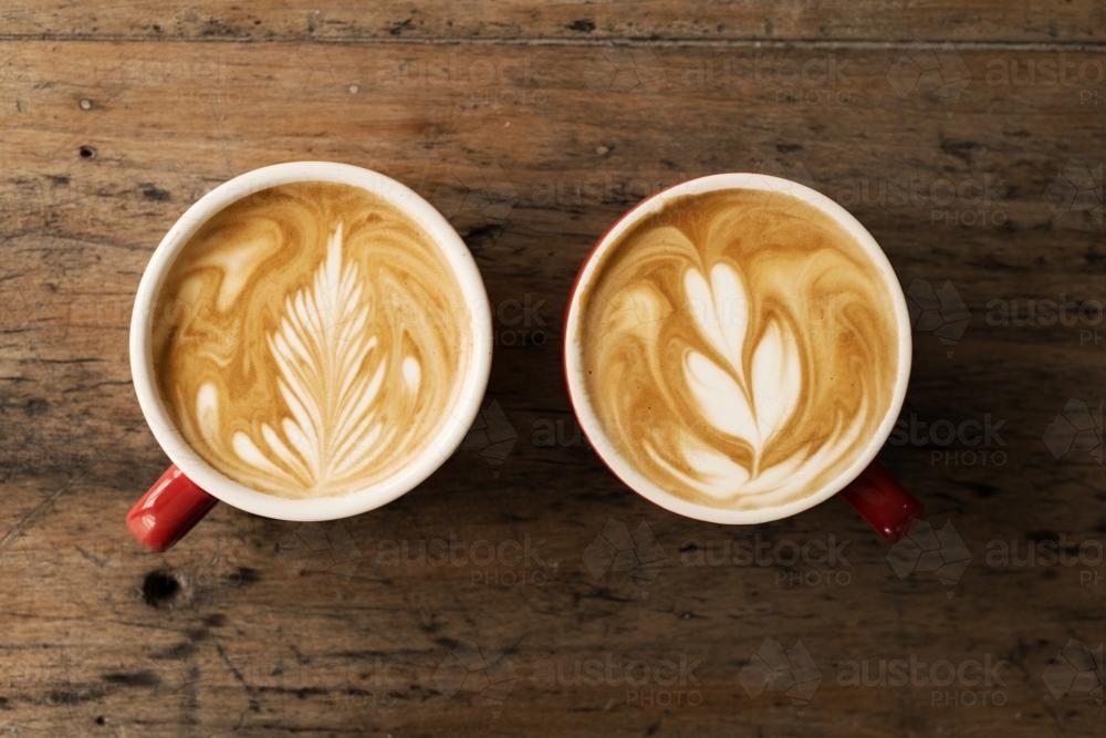 flat white coffees on a timber table, with beautiful latte art - Australian Stock Image