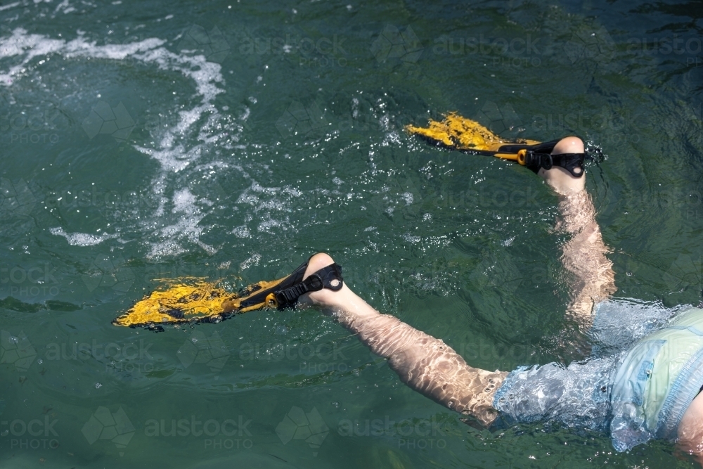 Flippers on child's feet while snorkeling in the ocean - Australian Stock Image