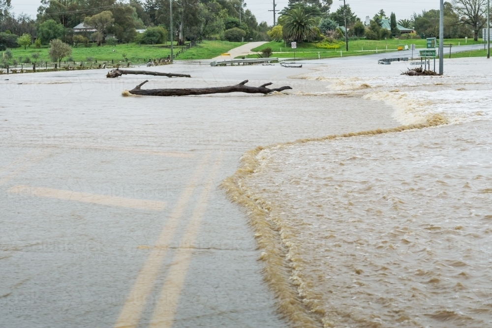 Flood waters and debris rushing over a highway - Australian Stock Image
