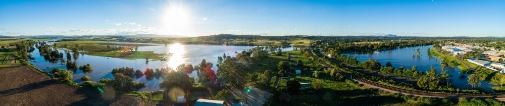Flooded farm land, netball courts and park beside overflowing river with water levels rising up - Australian Stock Image