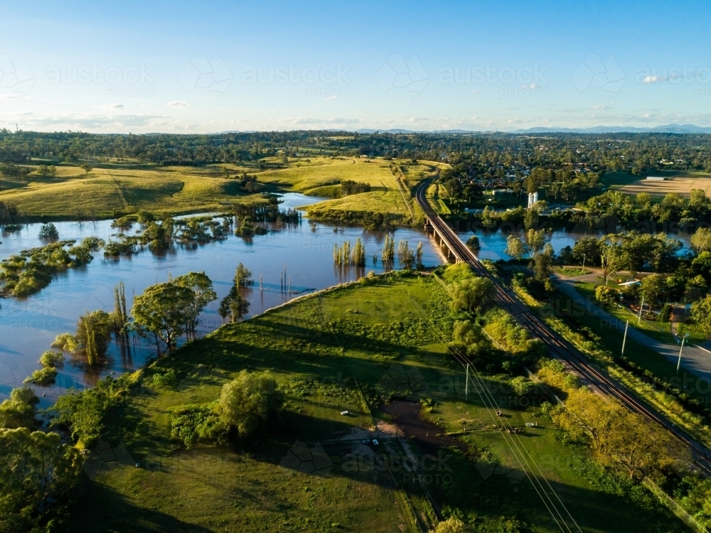 Flooded farmland and railway bridge crossing river in flood - Australian Stock Image