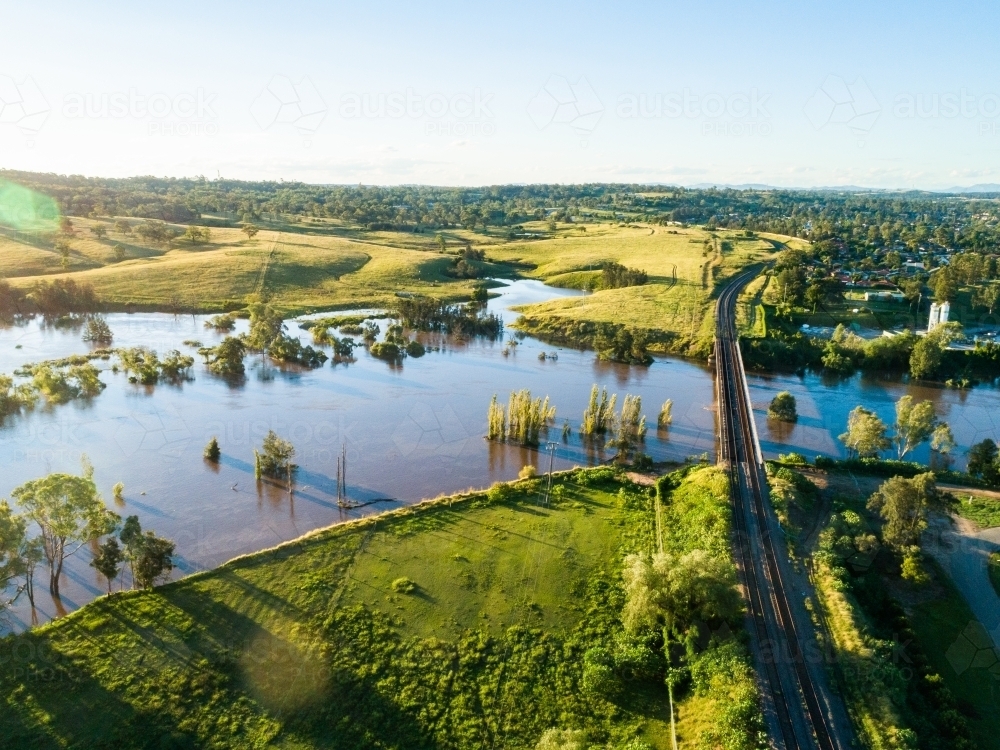 Flooded farmland and railway bridge crossing river in flood - Australian Stock Image