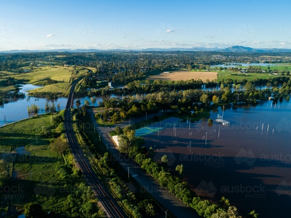 Flooded netball courts and park beside overflowing river with water levels still rising - Australian Stock Image