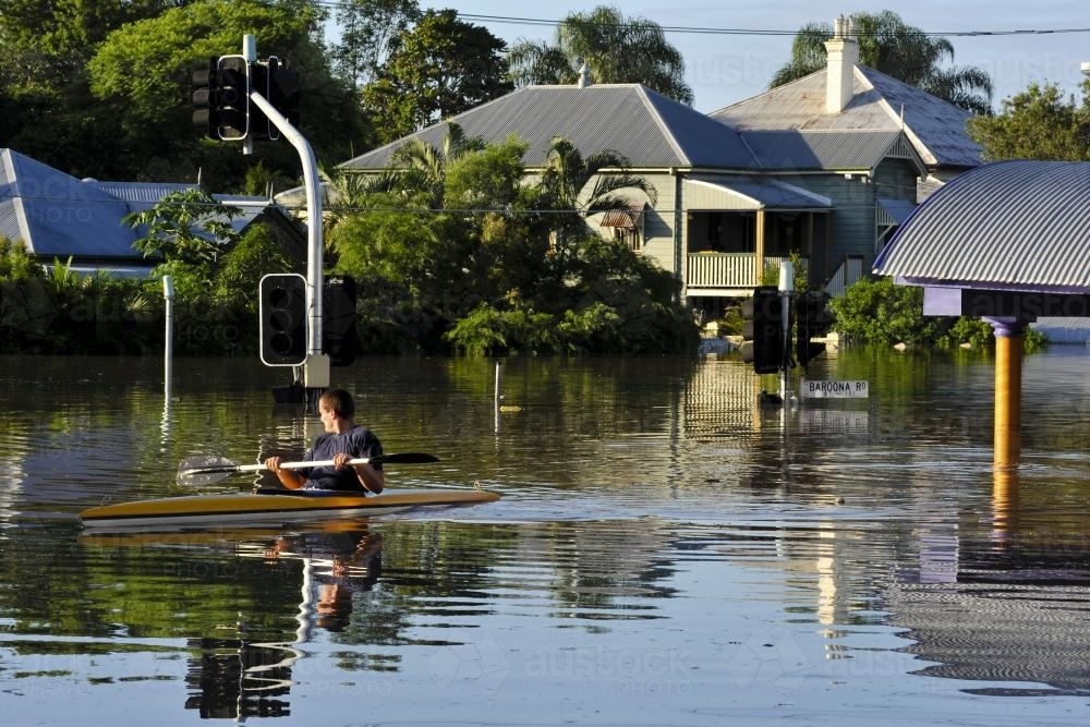 Flooded residential street with man in a canoe - Australian Stock Image
