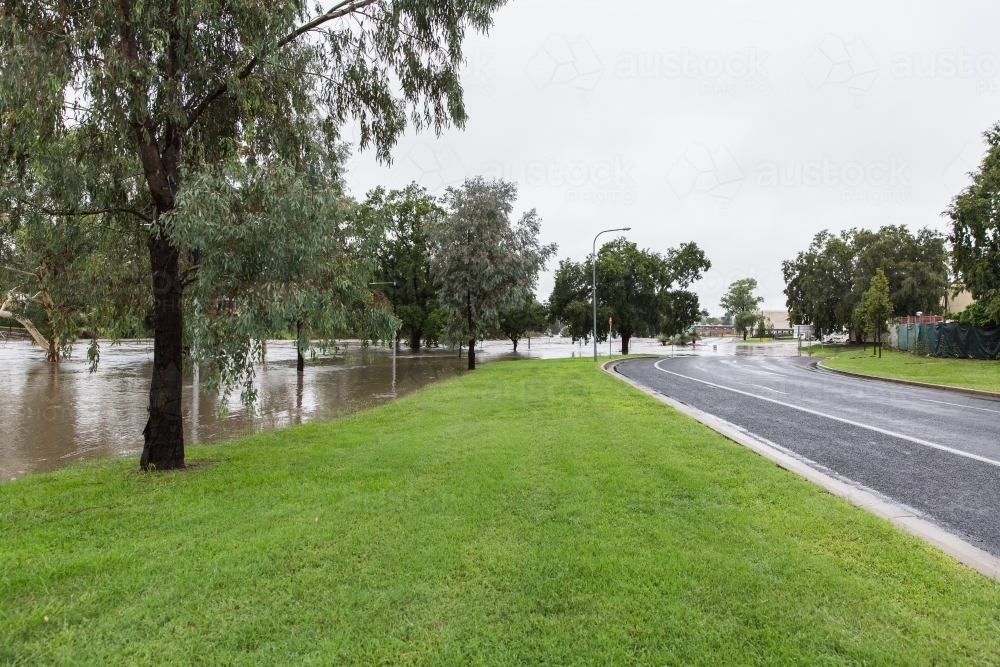 Flooded river next to main road in town - Australian Stock Image