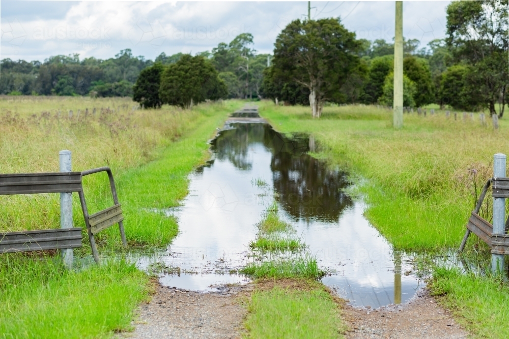 Flooded rural driveway entrance with water flowing over - Australian Stock Image