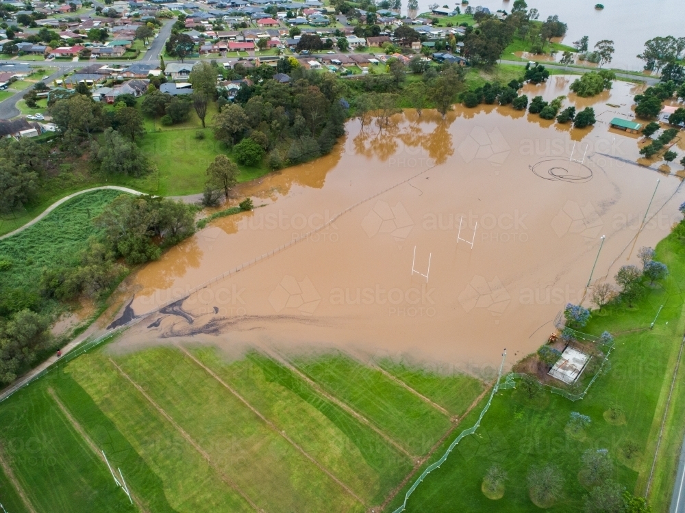 Flooded sports oval covered in brown floodwater - Australian Stock Image