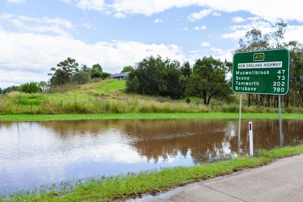Floodwater beside New England Highway with road sign - Australian Stock Image