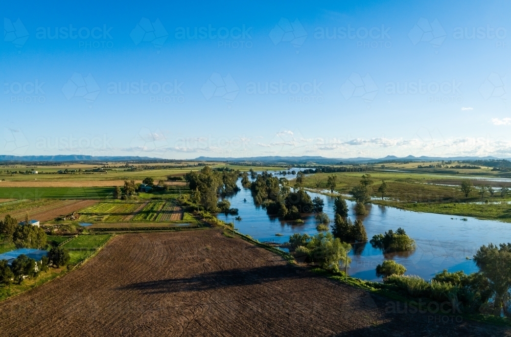 Floodwaters of river rising up and flooding over farmland - Australian Stock Image