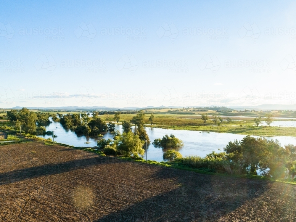 Floodwaters of river rising up and flooding over farmland - Australian Stock Image
