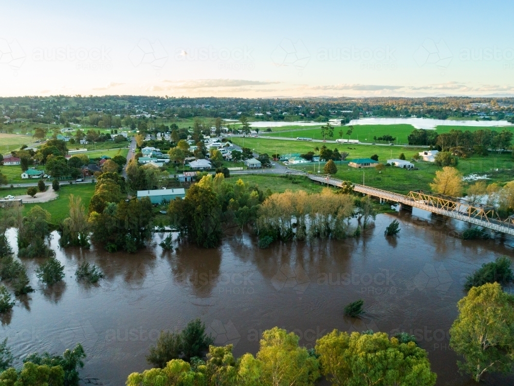 Floodwaters of river rising up towards houses and bridge - Australian Stock Image