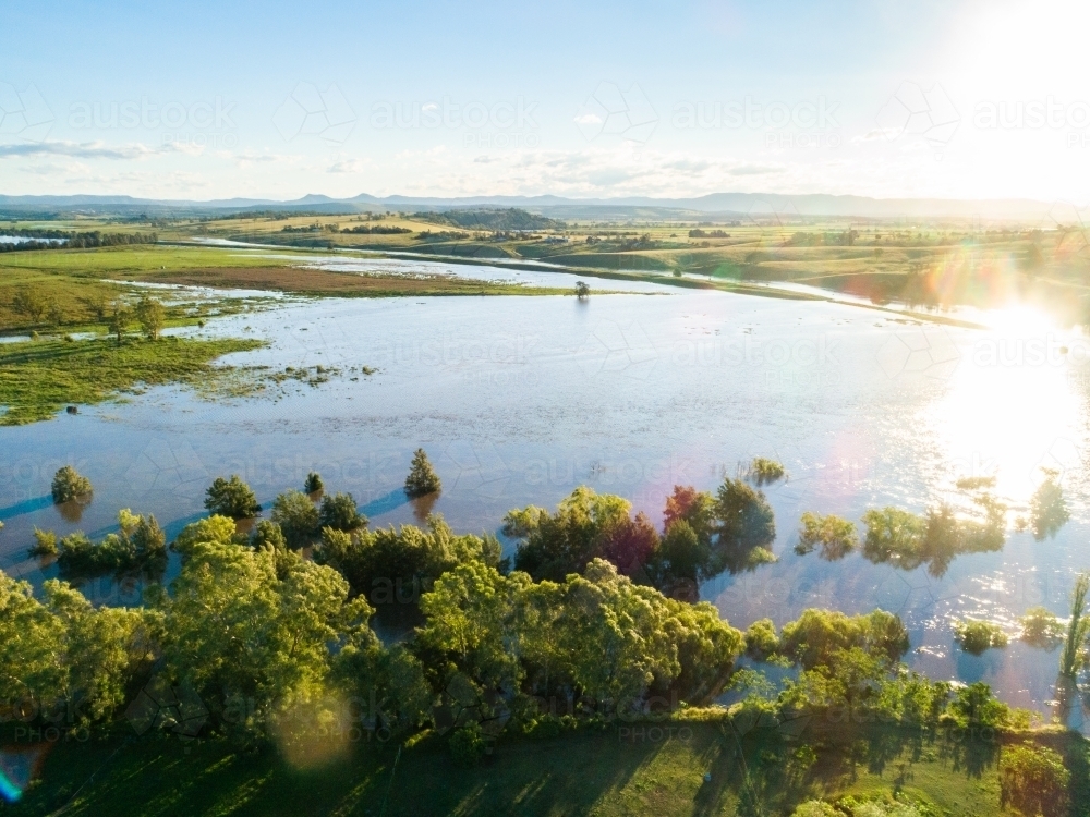 Floodwaters spread out over farmland beside overflowing river - Australian Stock Image