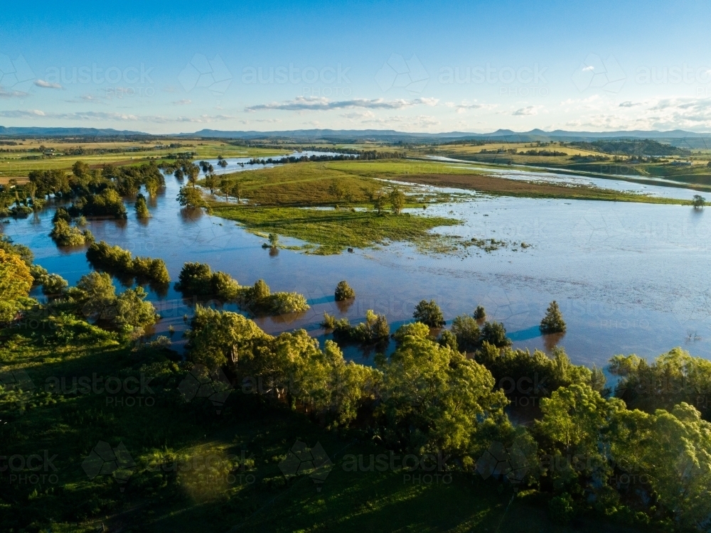 Floodwaters spread out over farmland beside overflowing river - Australian Stock Image