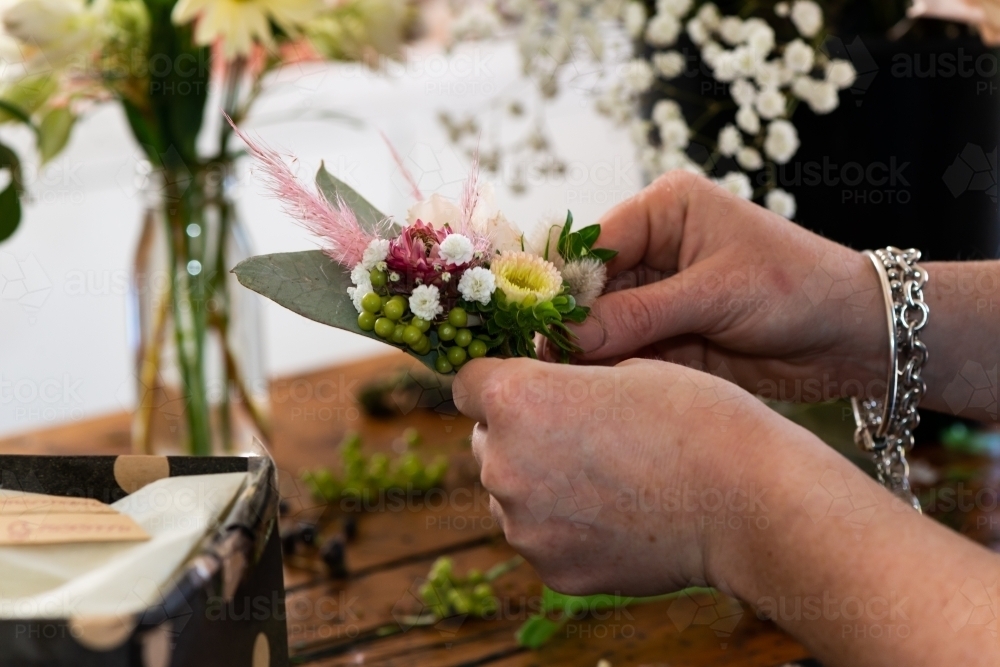 Florists hands holding a small pretty corsage for wedding, - Australian Stock Image
