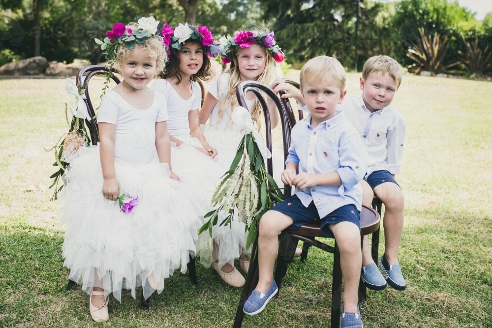 Flowergirls and pageboys sitting on chairs at wedding - Australian Stock Image