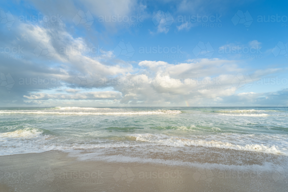 Foamy shore break waves on beach under soft clouds at Scarborough Beach, Perth, Western Australia - Australian Stock Image