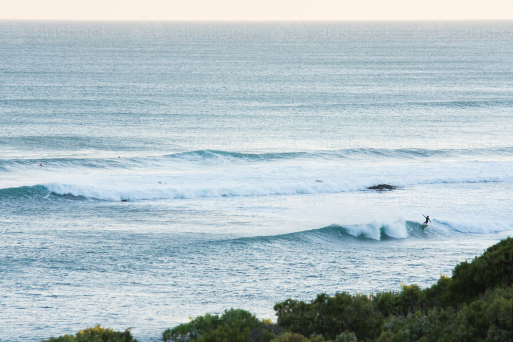 focus on horizon in foreground a lone surfer riding a wave - Australian Stock Image
