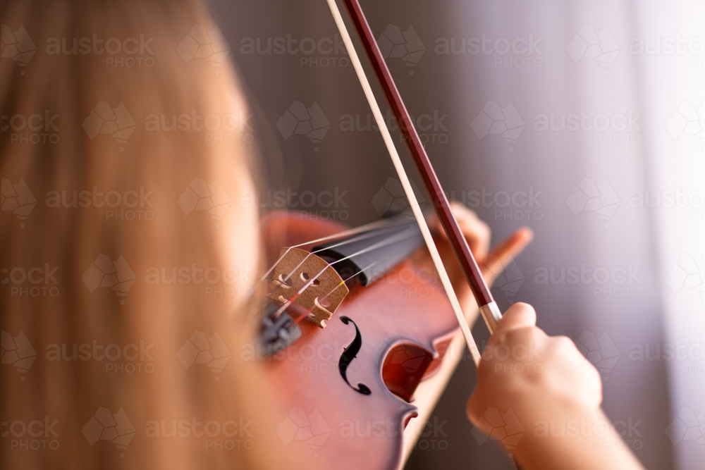 focus on violin bow, bridge and strings while a child plays - Australian Stock Image