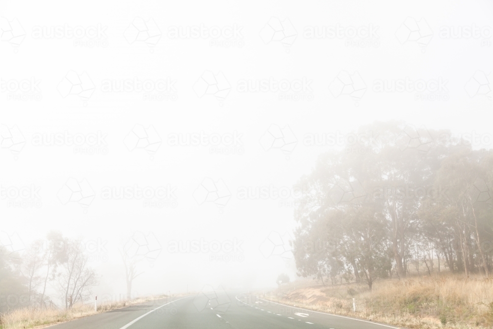 Fog hazardous driving condition with low visibility on road - Australian Stock Image