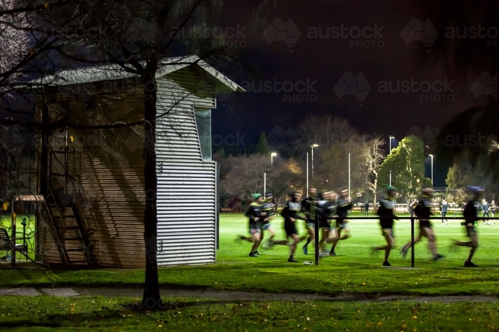 Image of Football team running laps around an oval on a winters night