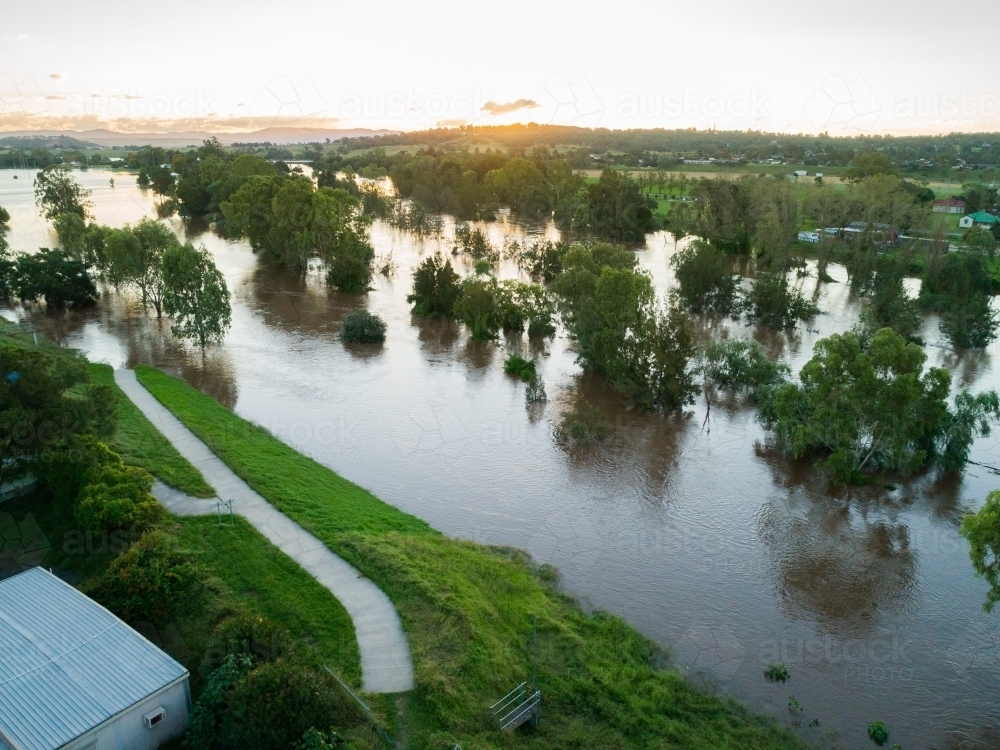 Footpath along levee bank ending in floodwaters of river - Australian Stock Image