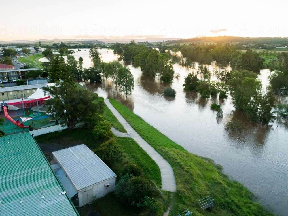 Footpath along levee bank ending in floodwaters of river - Australian Stock Image