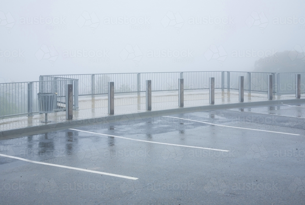 Footpath, railing and empty car park in mist and rain - Australian Stock Image