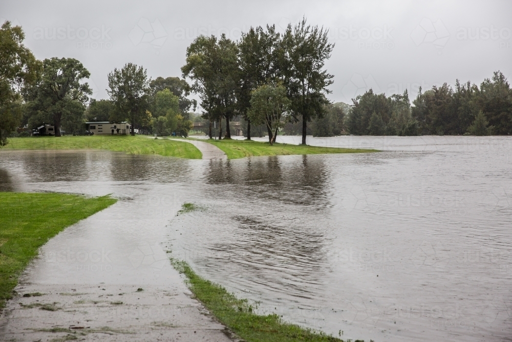 Footpath under flooded river water at park - Australian Stock Image