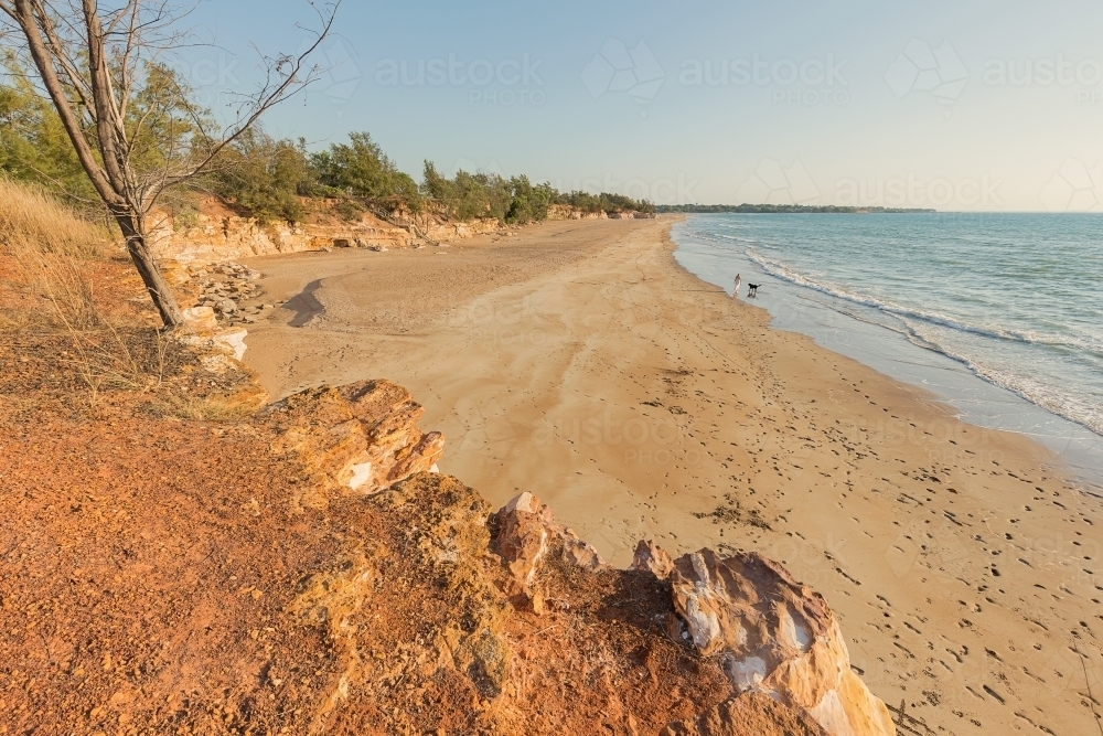 Footprints across Casuarina Beach, with distant person walking dog - Australian Stock Image