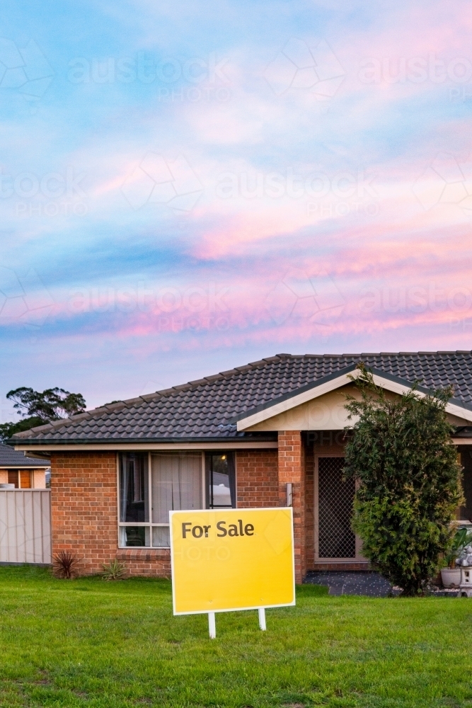 For Sale sign beside house at dusk with bright colours - Australian Stock Image