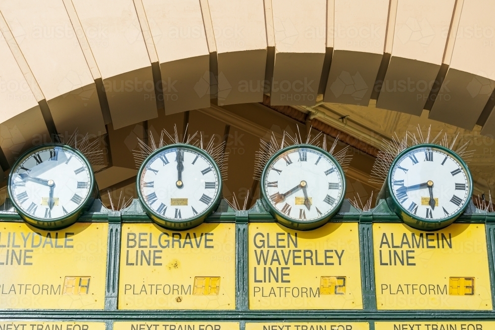 Four old fashioned railway clocks with bird spikes under a archway. - Australian Stock Image