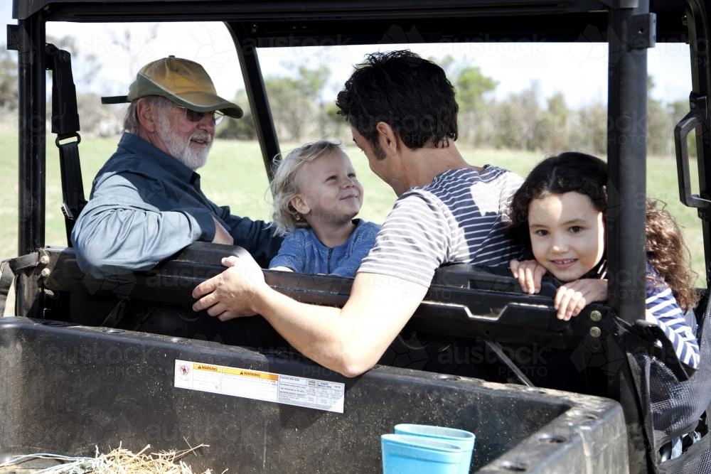Four people in a farm utility vehicle - Australian Stock Image