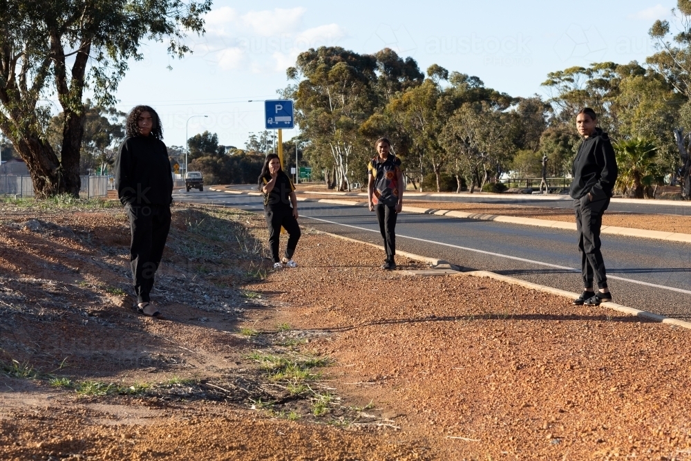 four teenagers black hanging out on side of road - Australian Stock Image