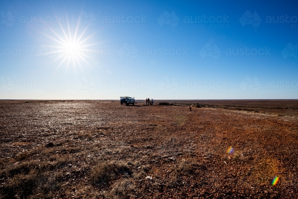 four wheel drive and people in brown landscape with blue sky and blazing sun - Australian Stock Image