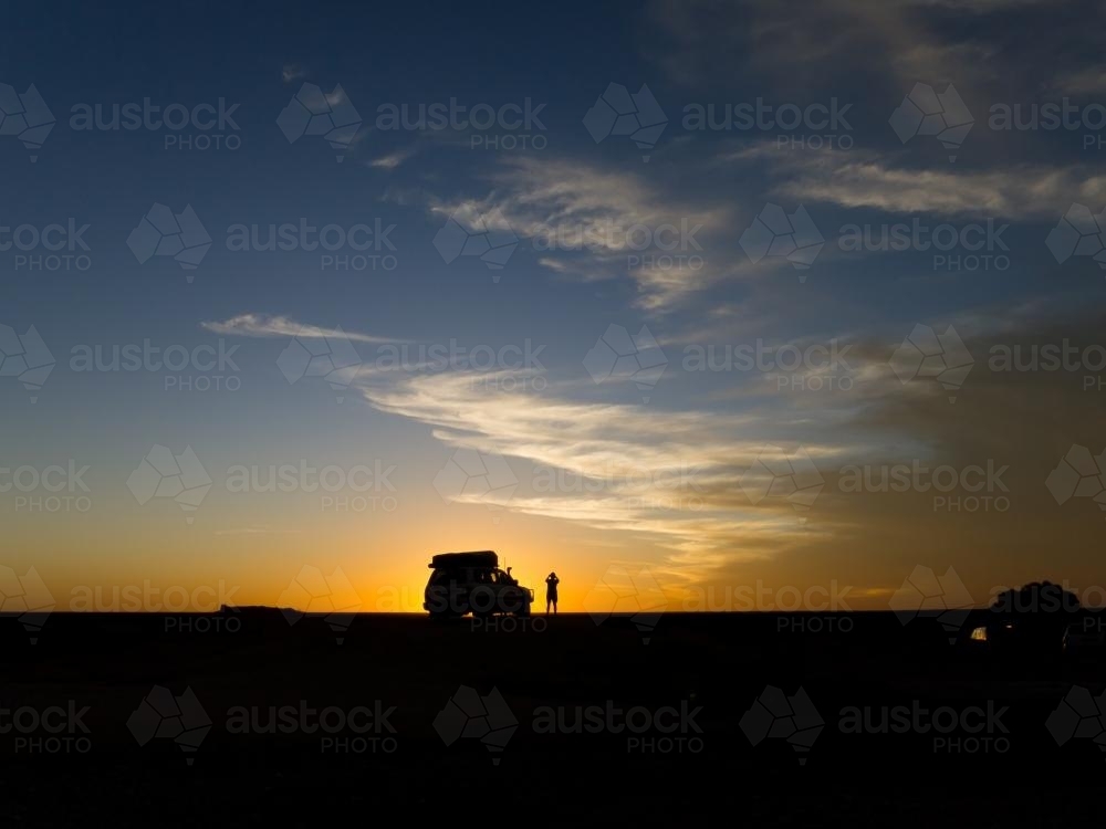 Four wheel drive vehicle and a person silhouetted against the sunset : Austockphoto Four wheel drive vehicle and a person silhouetted against the sunset - Australian Stock Image