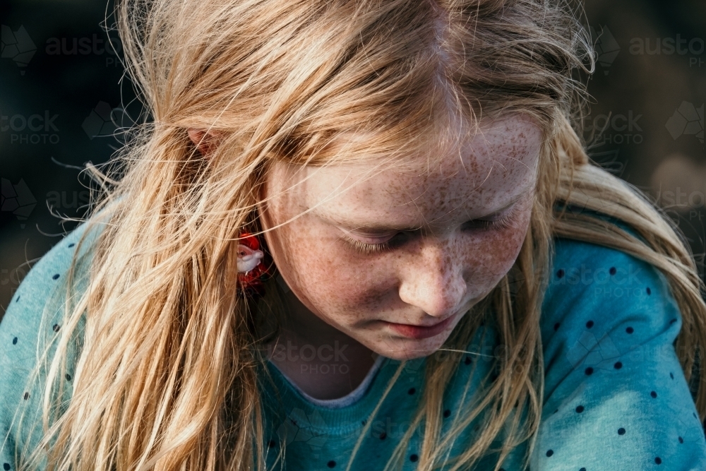 Young girl with freckles and spots on her face looking down - Australian Stock Image