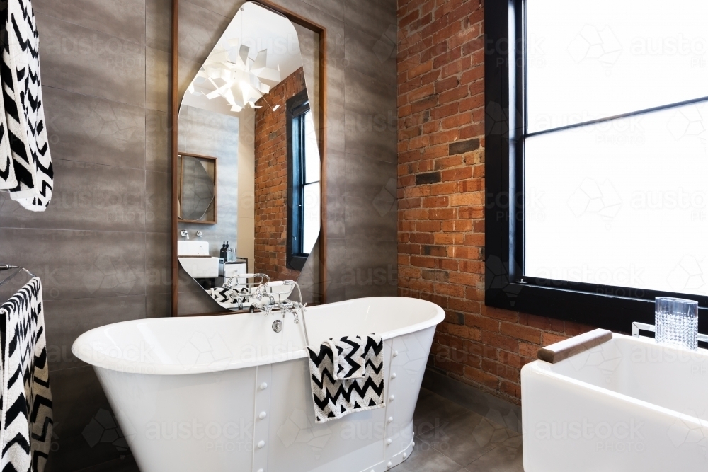 Freestanding vintage style white bath tub in renovated warehouse apartment - Australian Stock Image
