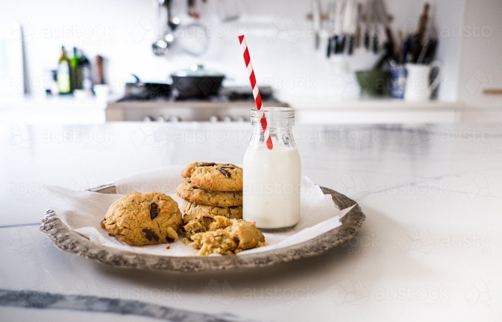 Fresh baked chocolate chip cookies and milk on the kitchen bench. - Australian Stock Image