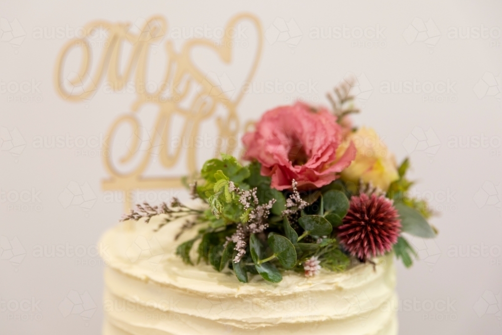 fresh flowers on top of simple wedding cake - Australian Stock Image