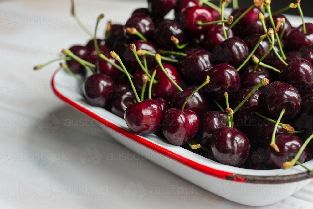 fresh juicy cherries in an old enamelware dish - Australian Stock Image