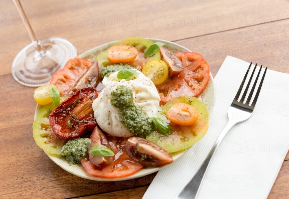 Fresh multiple coloured tomato salad with buffalo mozzarella and green basil pesto - Australian Stock Image