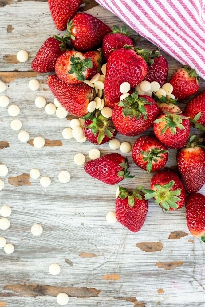 fresh strawberries and white chocolate bits on a wooden background - Australian Stock Image