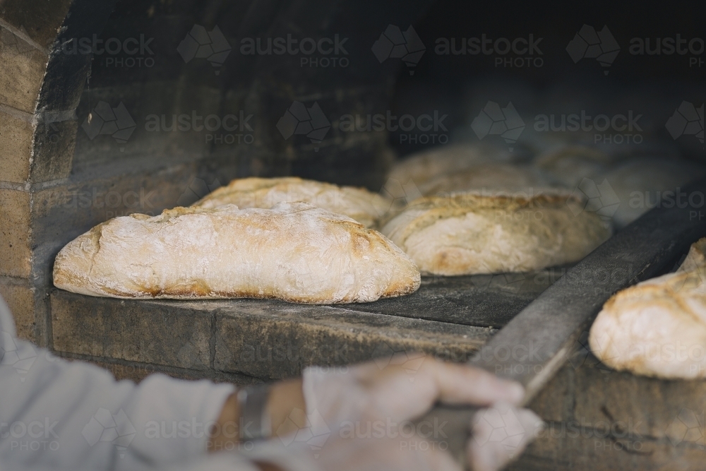Freshly baked bread, being pulled out of the oven - Australian Stock Image