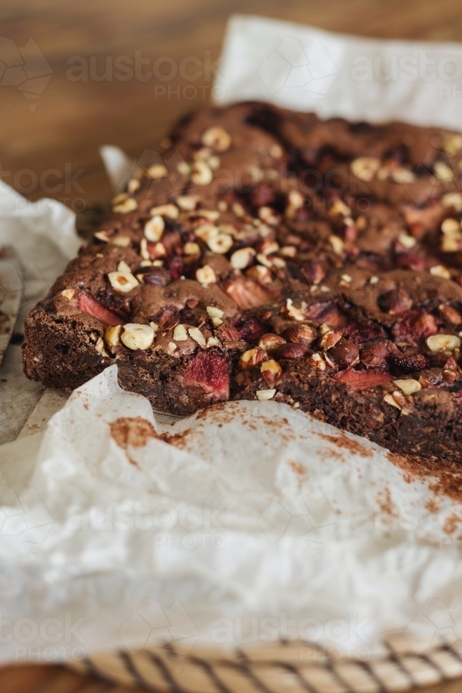 freshly baked chocolate brownie with hazelnuts and strawberries - Australian Stock Image